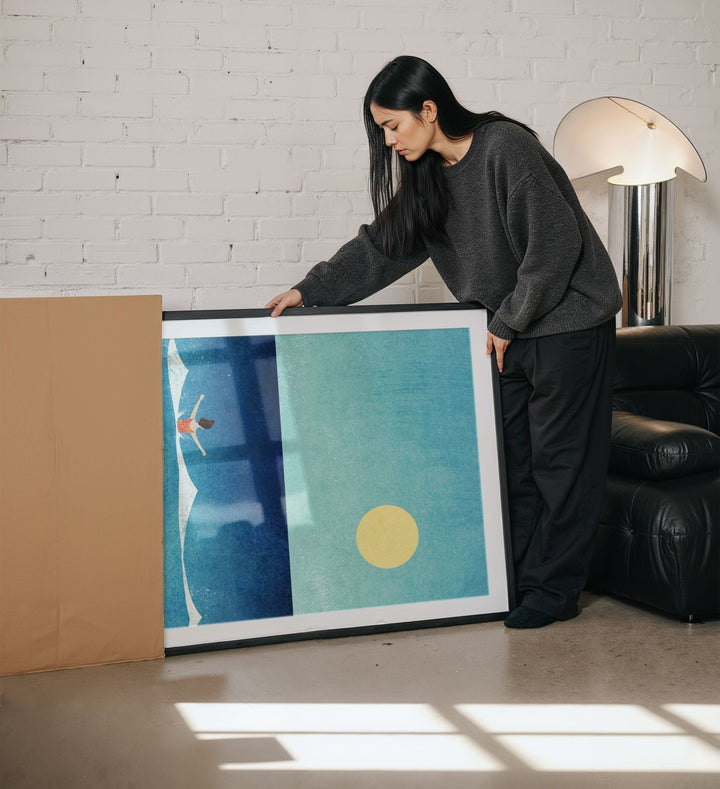 Woman holding an abstract artwork in a living room.