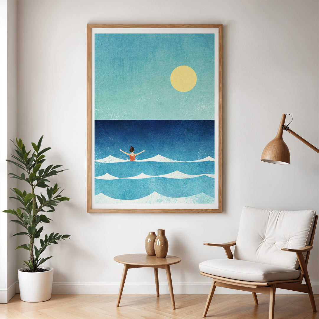 Artwork of a person in the ocean with a sun above, displayed in a room with a chair and plant.