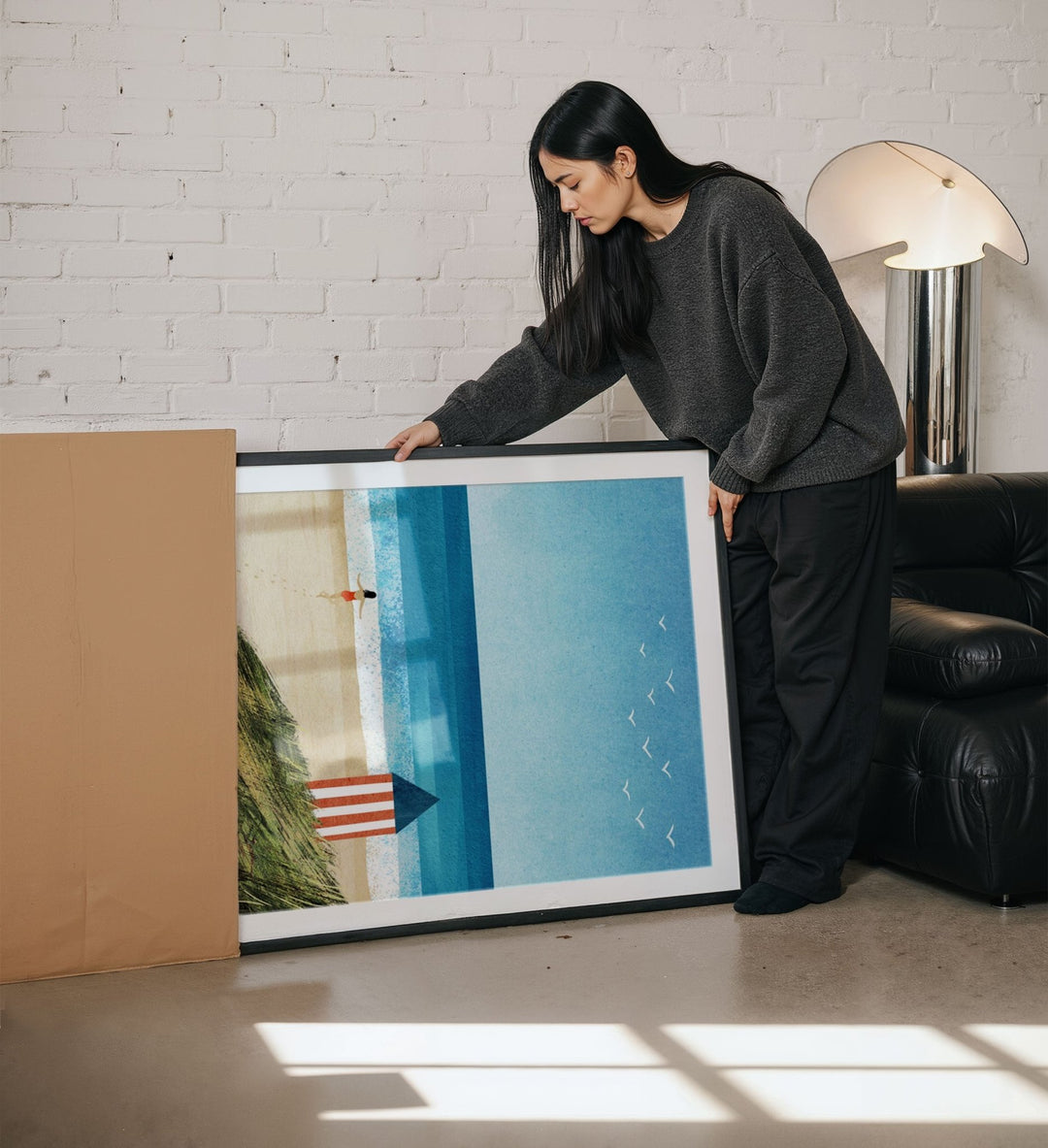 Woman holding an artwork in a living room.