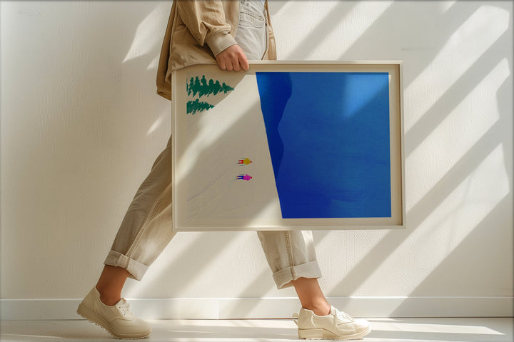 Person holding two artworks with abstract designs against a white wall.