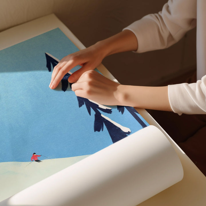 Person unrolling a large poster of a scenic landscape with a person on a hill.