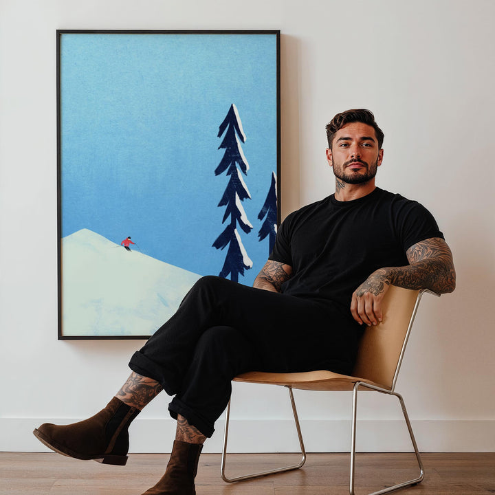Man sitting on a chair in a room with an artwork of trees and mountains.
