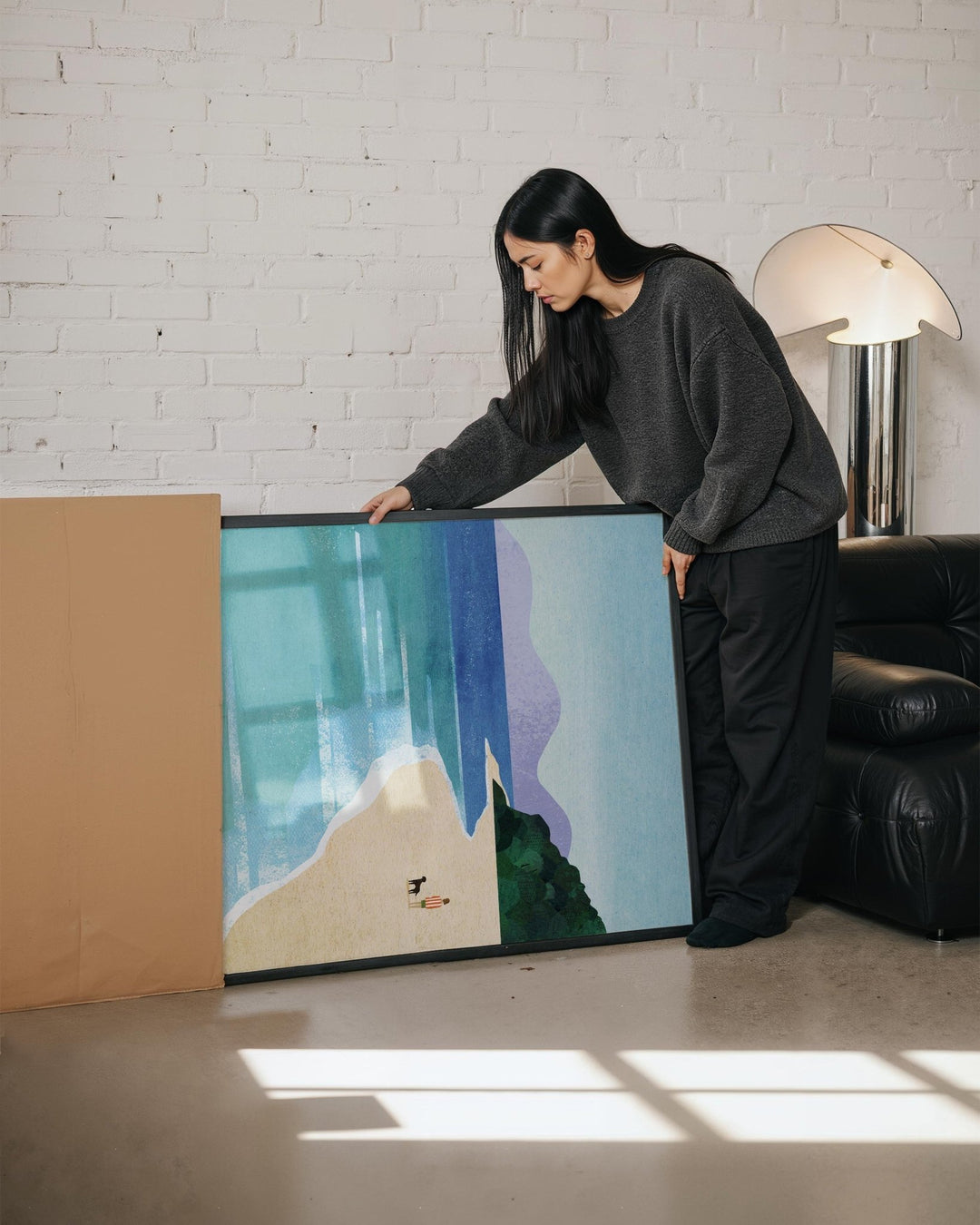 Person standing next to a large abstract painting in a room with a white brick wall and a lamp.