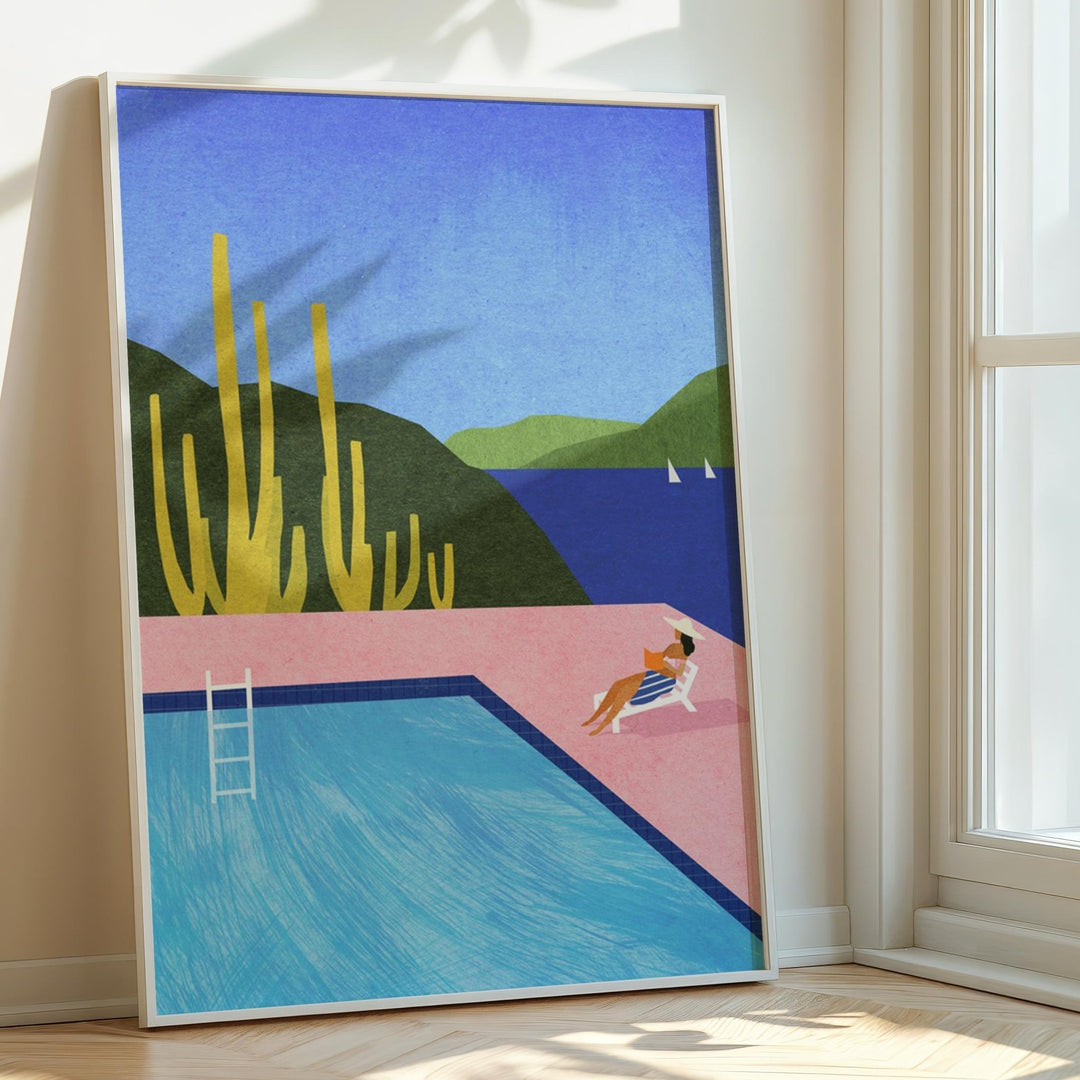 Artwork of a pool scene with cacti and a person lounging, placed on a wooden floor.