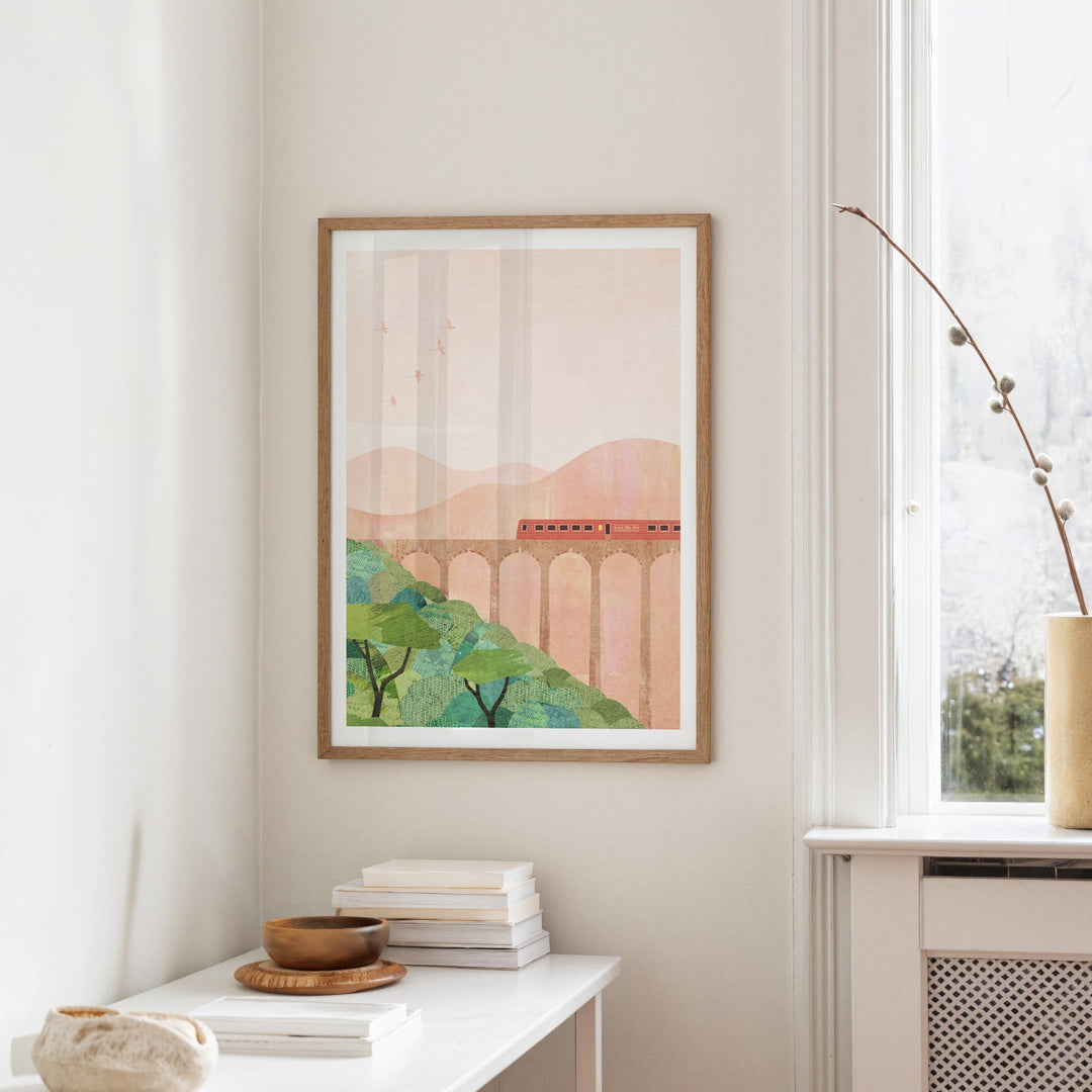Artwork of a landscape with a bridge on a wall in a room.