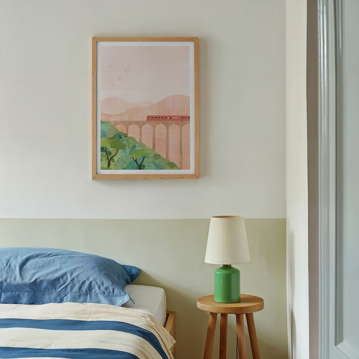 Bedroom with a bed, lamp, and  artwork on the wall.