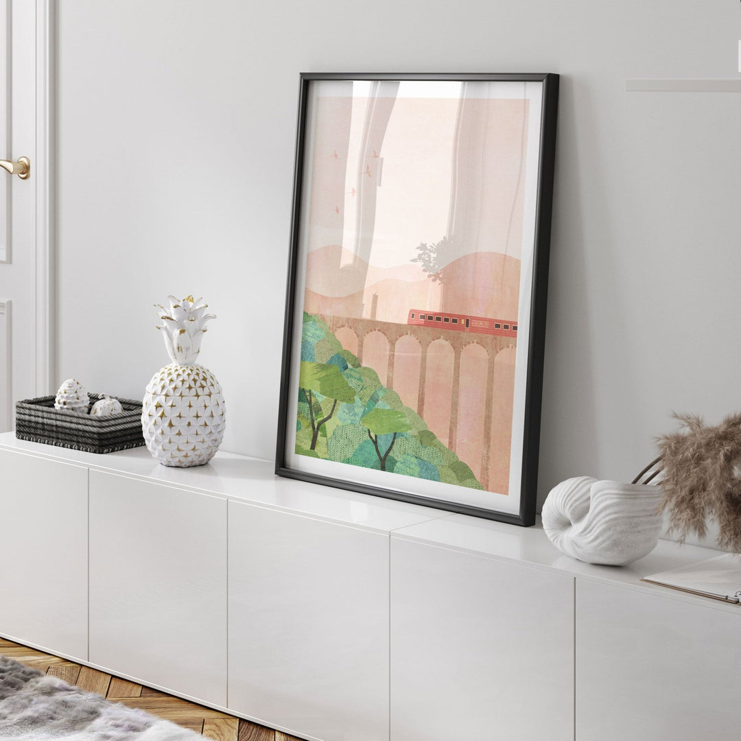 Artwork on a white wall above a white cabinet with decorative items.