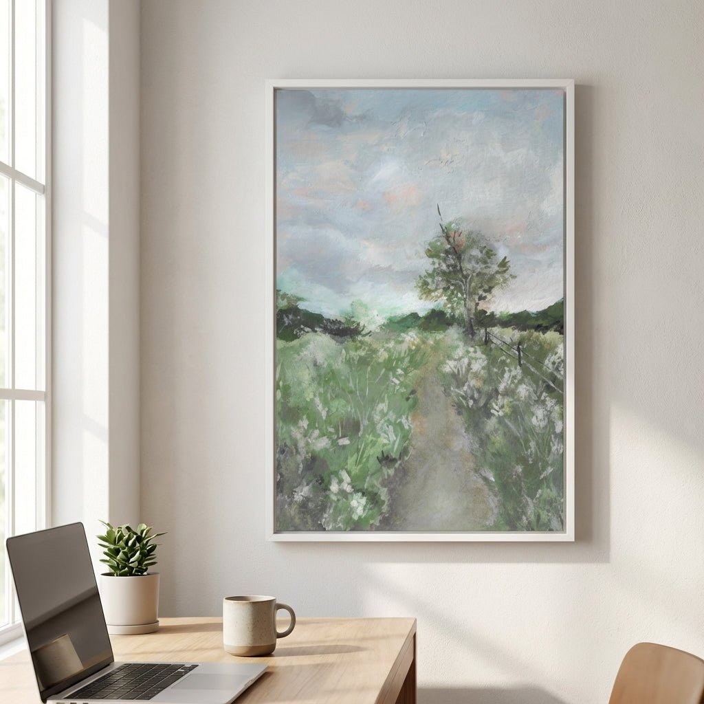 landscape painting on a wall above a desk with a laptop and mug.