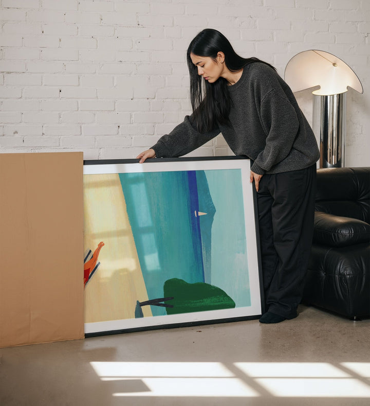 Woman holding an artwork in a living room.