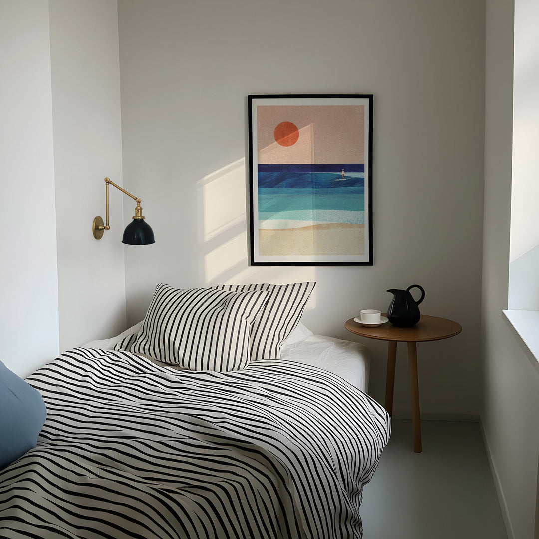 Modern bedroom with striped bedding, side table, and abstract wall art.