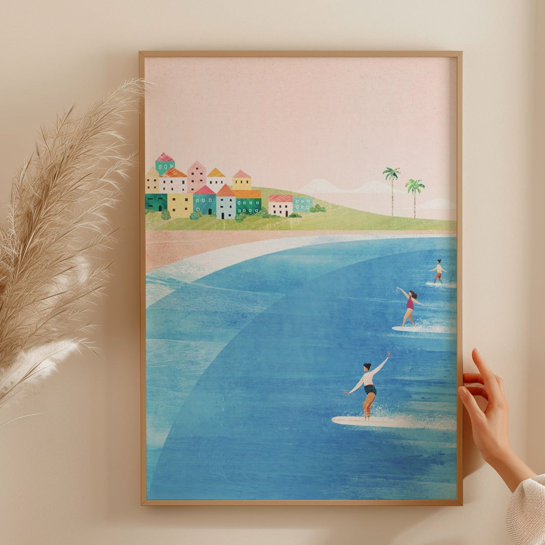 Artwork of a beach scene with people on surfboards, held by a hand against a light wall.