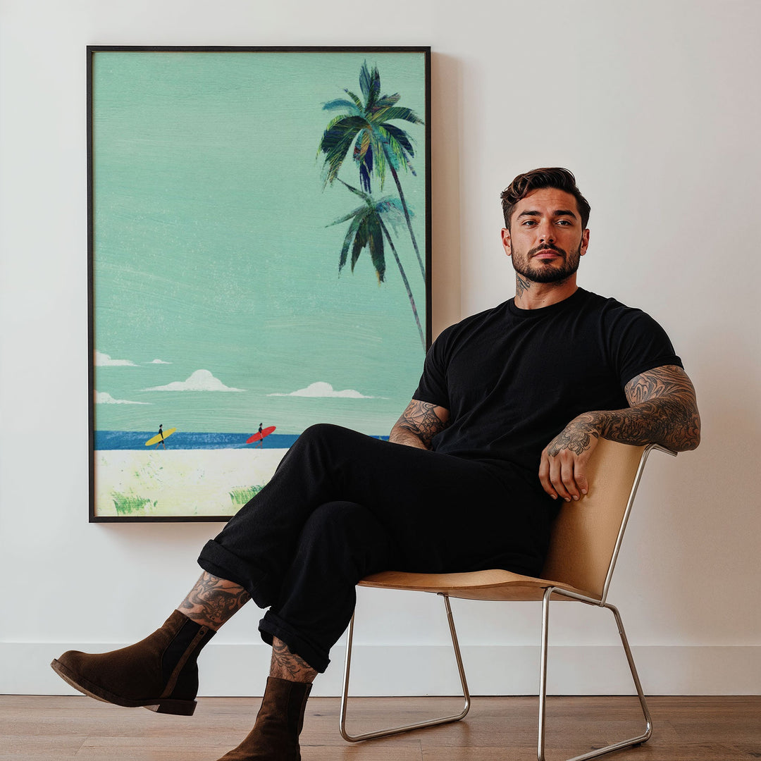 Man sitting on a chair in a room with  artwork of palm trees on the wall.