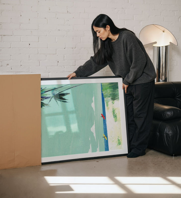 Woman holding a large artwork in a living room.