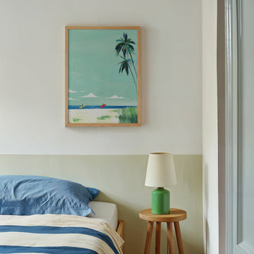 Artwork of a beach scene with palm trees above a bed in a bedroom.