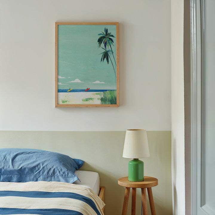Artwork of a beach scene with palm trees above a bed in a bedroom.