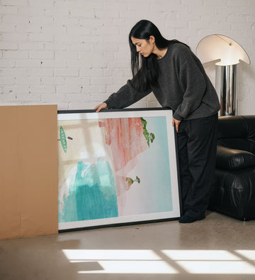Woman unboxing an artwork in a living room.