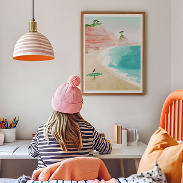 Person wearing a pink beanie sitting at a desk with a beach-themed poster on the wall.