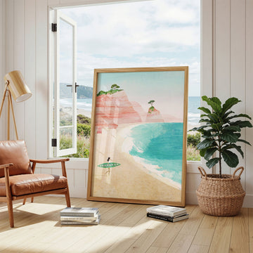 Beach artwork in a room with a leather chair, plant, and books.