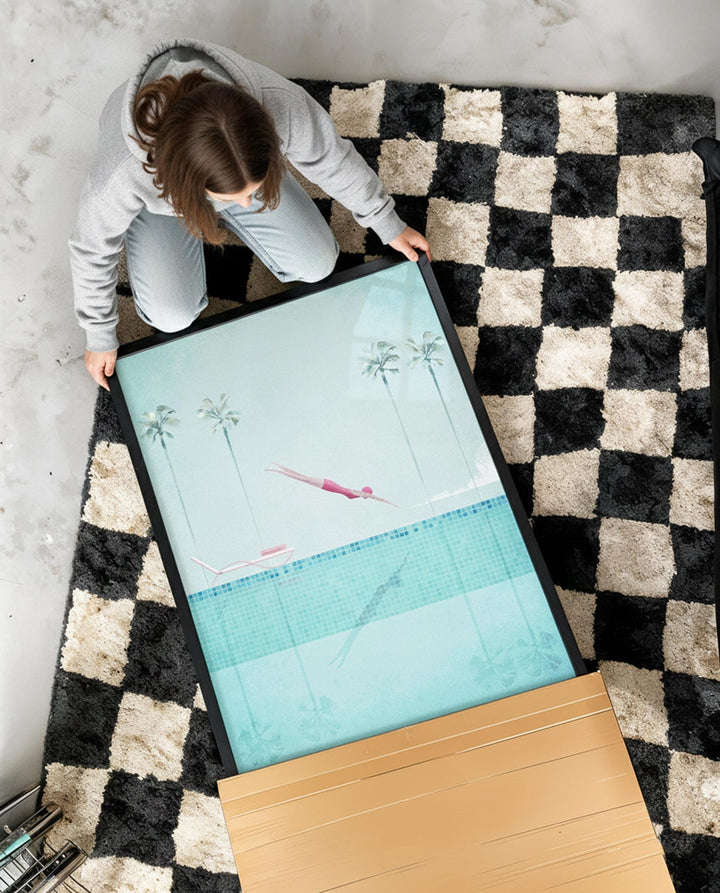 Person setting up a large screen on a checkered rug