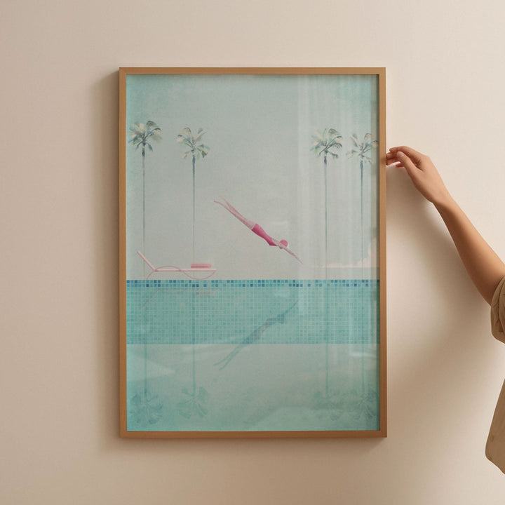 Artwork of a pool scene with palm trees and a person in a pink swimsuit, held by a hand against a beige wall.
