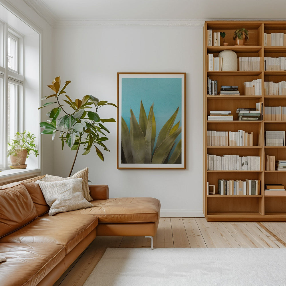 Modern living room with a brown leather sofa, bookshelf, and artwork.