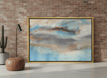 Oversized statement canvas wall art with a gold leaf surround leaning against the wall in an industrial loft living room