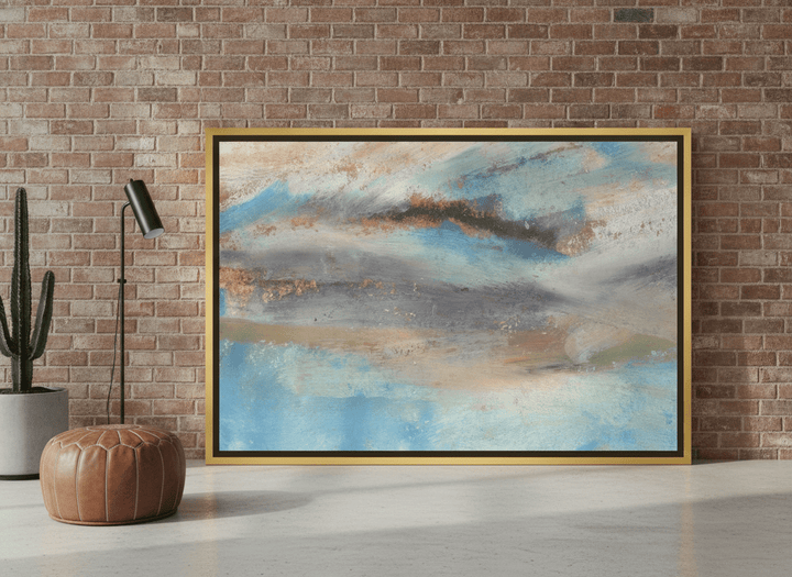 Oversized statement canvas wall art with a gold leaf surround leaning against the wall in an industrial loft living room