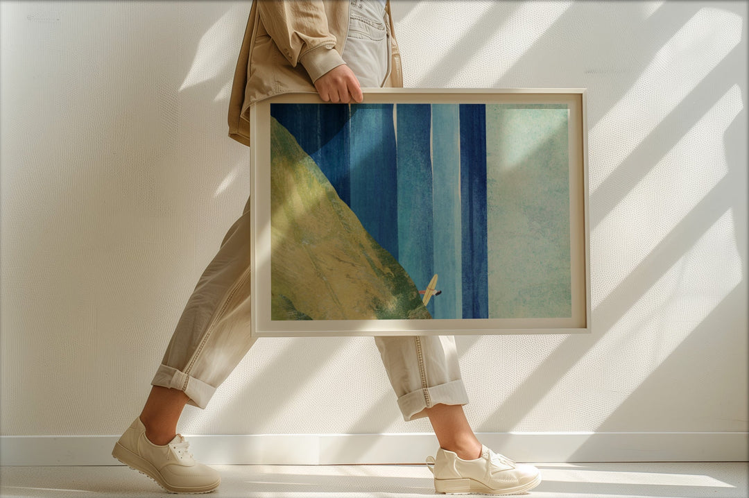 Person holding an abstract art piece with blue and green colors in a bright room.
