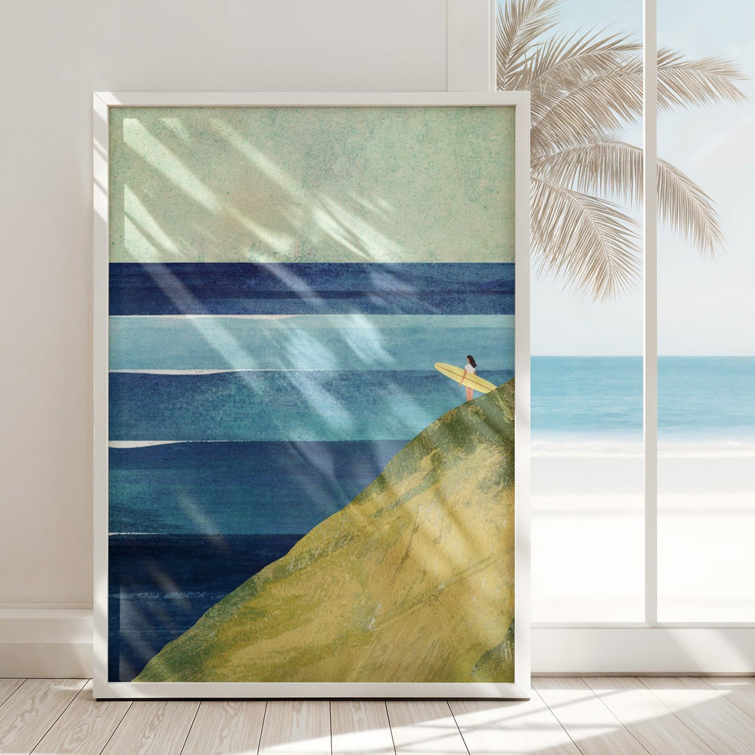 Artwork of a beach scene with a person on a yellow surfboard, placed in a room with a window showing palm trees.