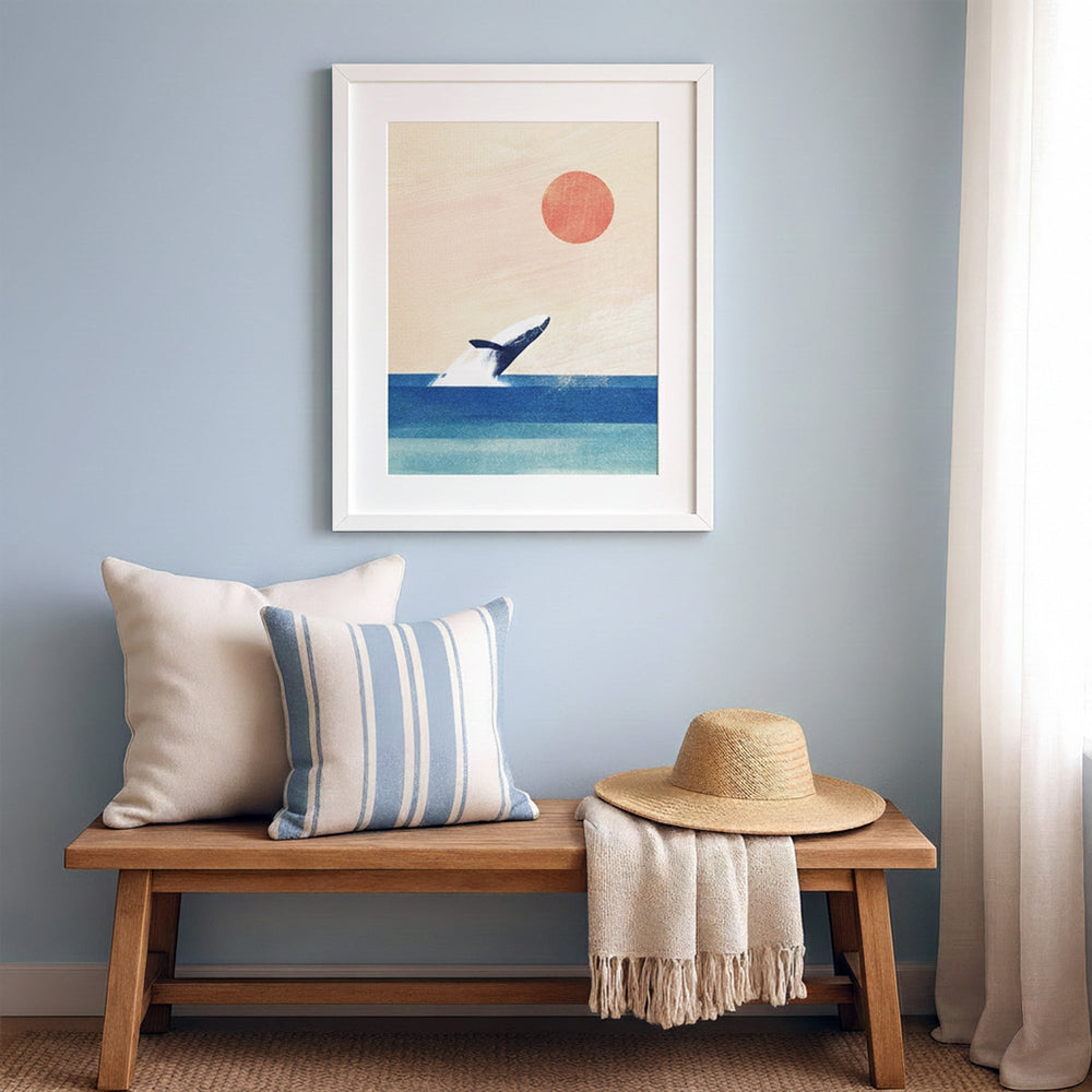 Wooden bench with pillows and a hat against a wall with an artwork of a whale and sun.