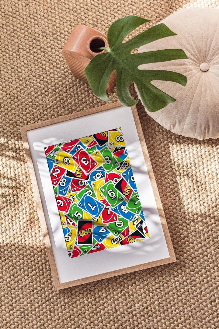 Colorful UNO artwork on a textured surface with a plant and vase.