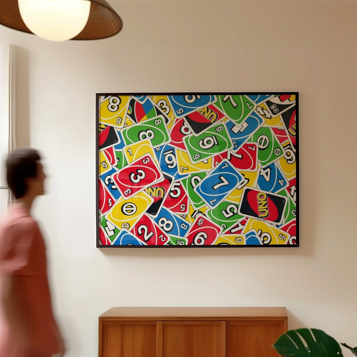 Artwork with colorful card designs on a wall, person walking by