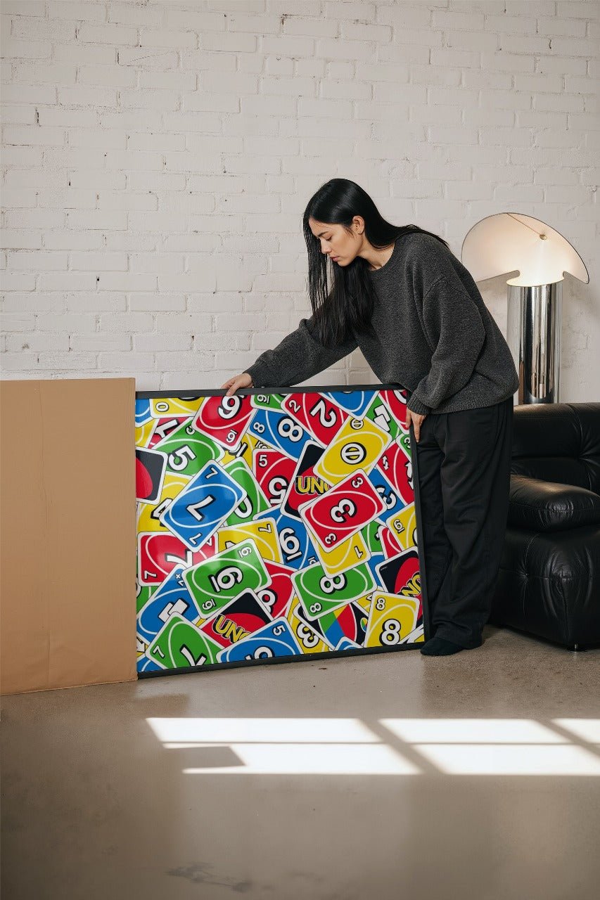 Person holding a colorful box with numbers and letters against a white brick wall.