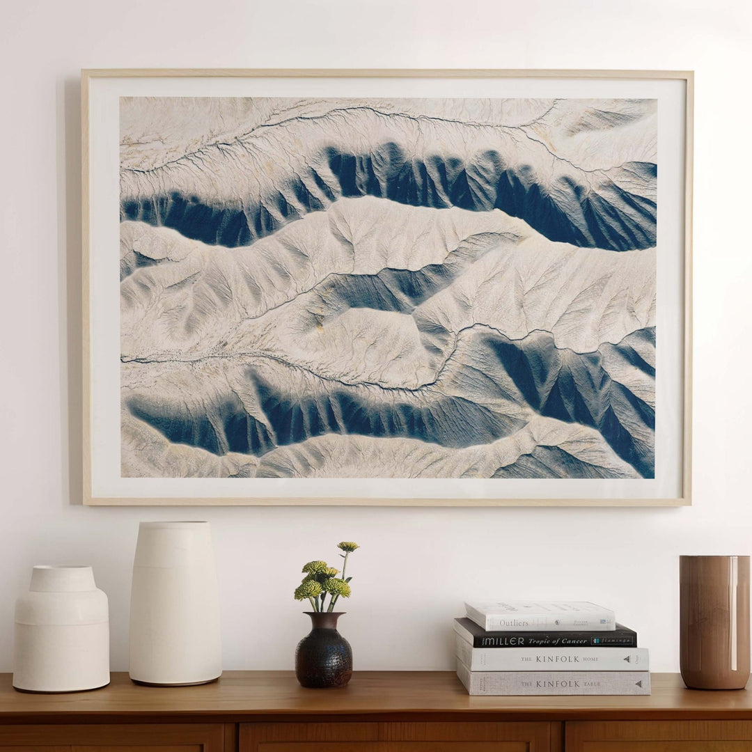 Wooden sideboard with decorative items and a landscape print on a wall.