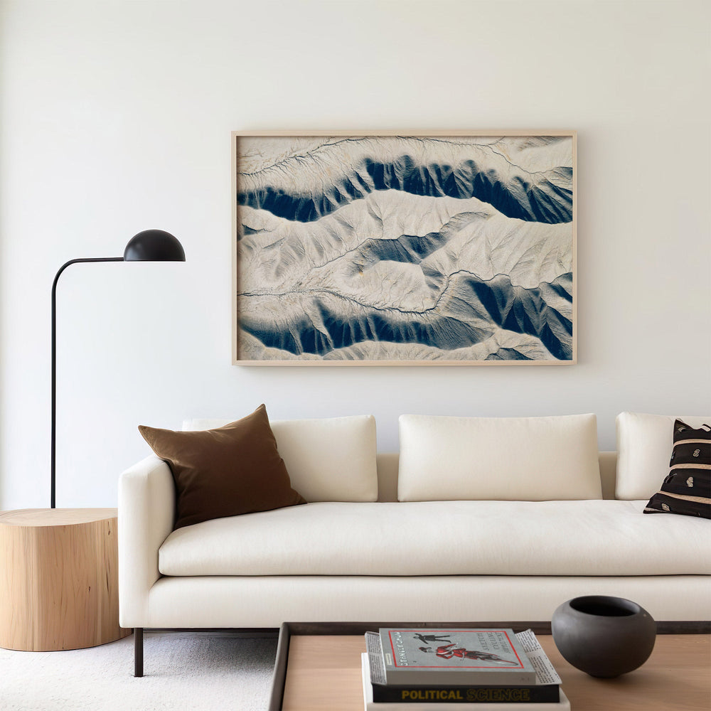 Modern living room with a white sofa, mountain landscape art, and a lamp.