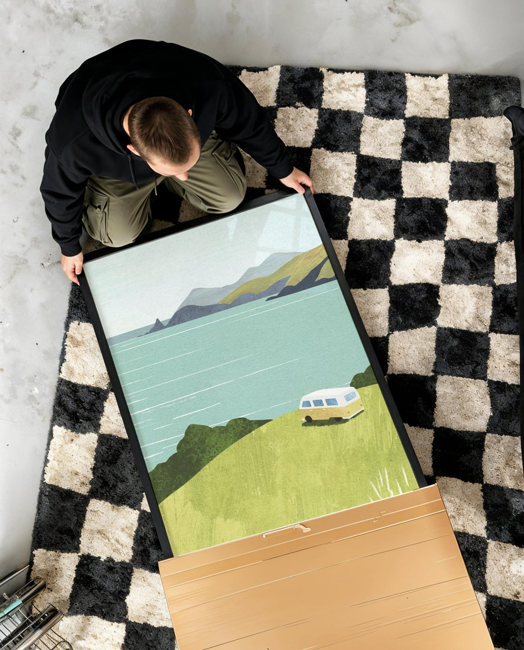 Person unboxing a scenic poster on a checkered rug