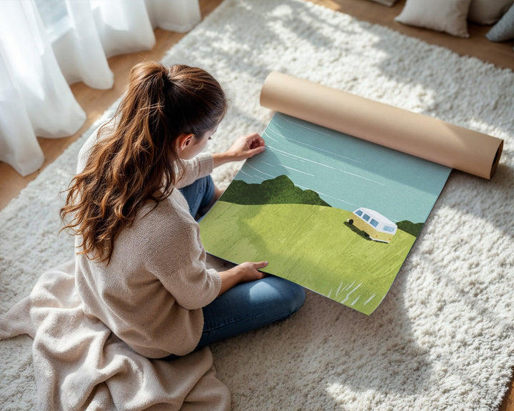Woman unrolling a green and blue landscape rug on a light-colored floor.