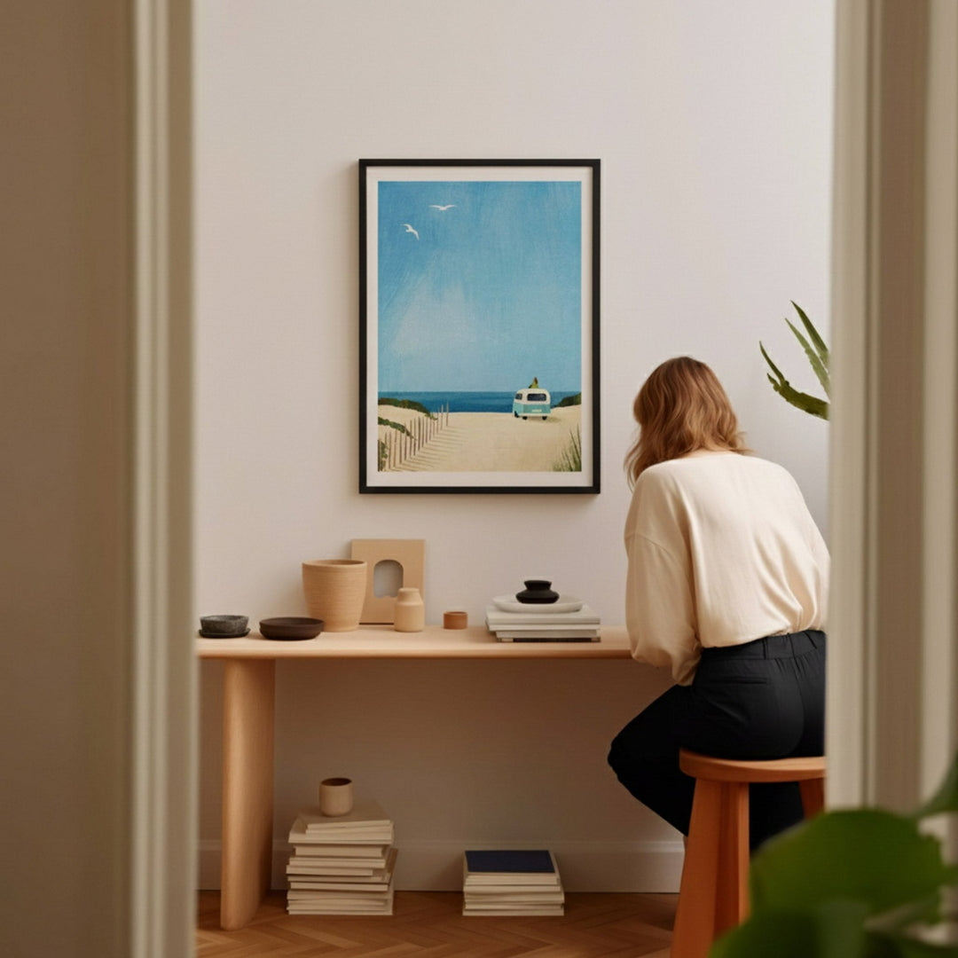 Person sitting at a desk in a room with artwork on the wall.