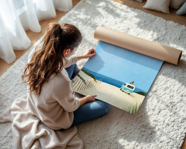 Woman unrolling a large poster of a scenic landscape on a carpeted floor.