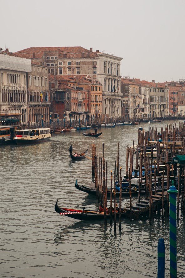 Venetian canal with gondolas and boats near historic buildings framed