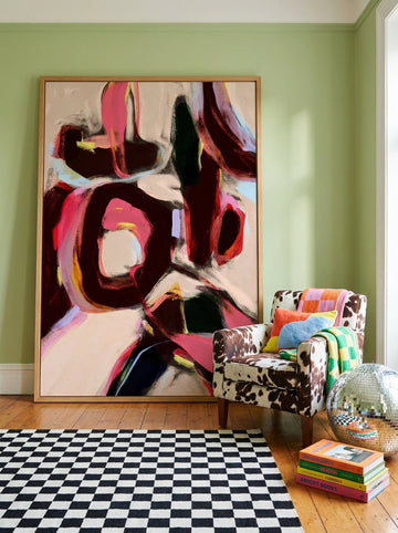 Oversized statement modern wall art print leaning against the wall in a colourful eclectic dining room