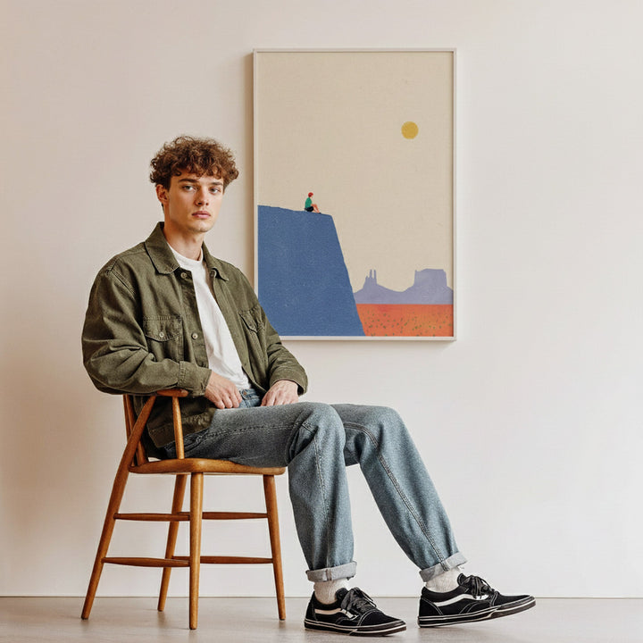 Man sitting on a wooden stool in a room with a colorful abstract painting on the wall.