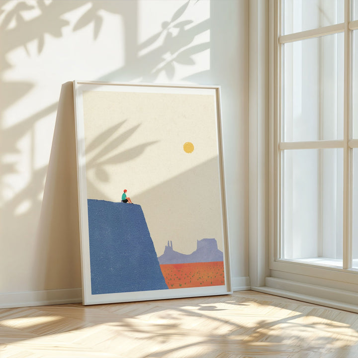 Artwork of a desert landscape with a blue hill and red sand, placed on a light wooden floor.