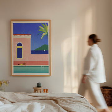 Woman walking past a painting of a poolside scene in a bedroom.