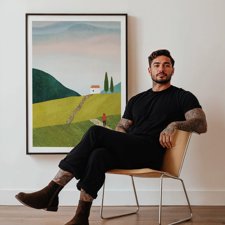 Man sitting on a chair in a room with a landscape painting on the wall.