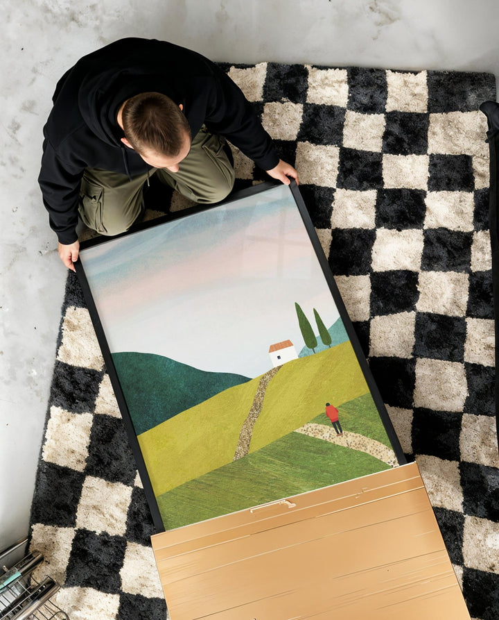 Person holding a landscape print on a checkered rug