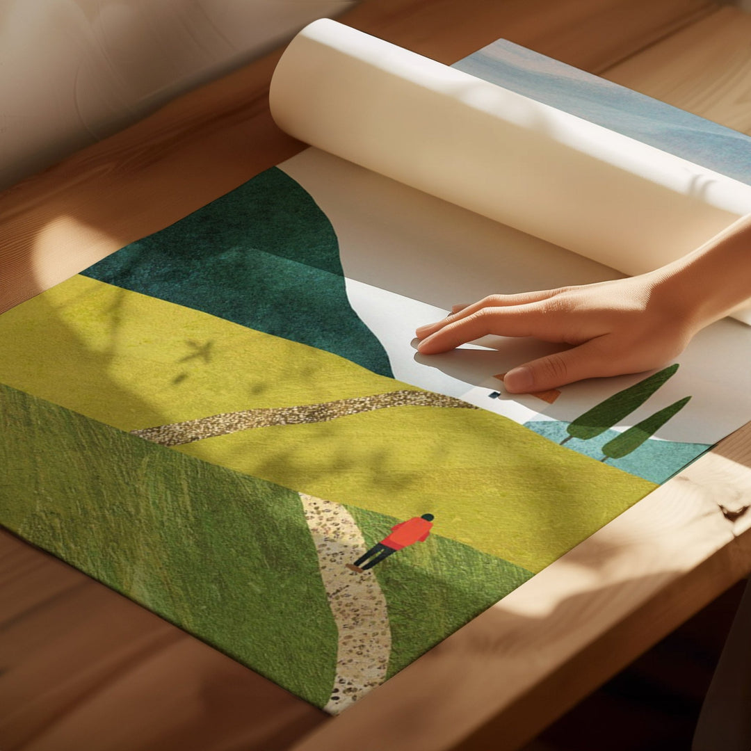 Person holding a rolled-up green landscape design on a wooden surface