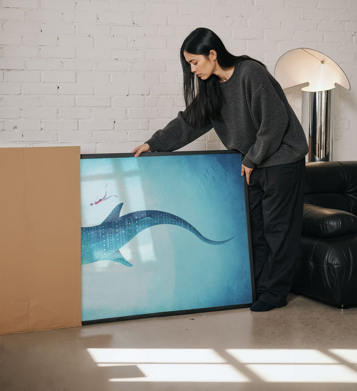 Woman unboxing artwork of a blue whale in a living room.