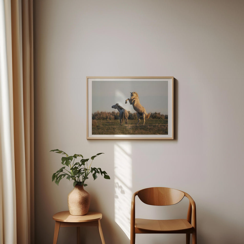 Artwork of two horses on a wall with a plant and chair below.