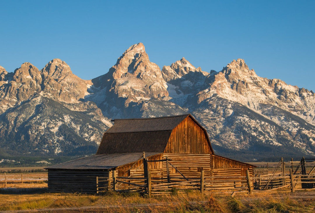Wooden barn with snow-capped mountains in the background framed